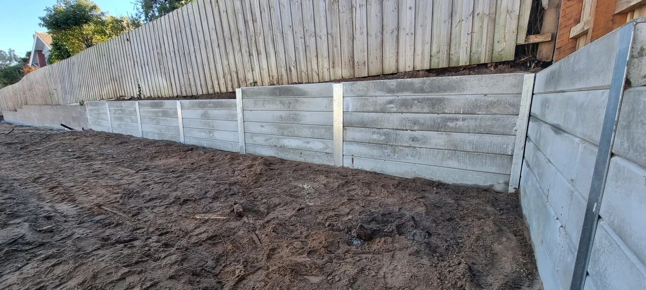 Stepped concrete sleeper retaining wall and steel posts beside the boundary fence in Bentleigh