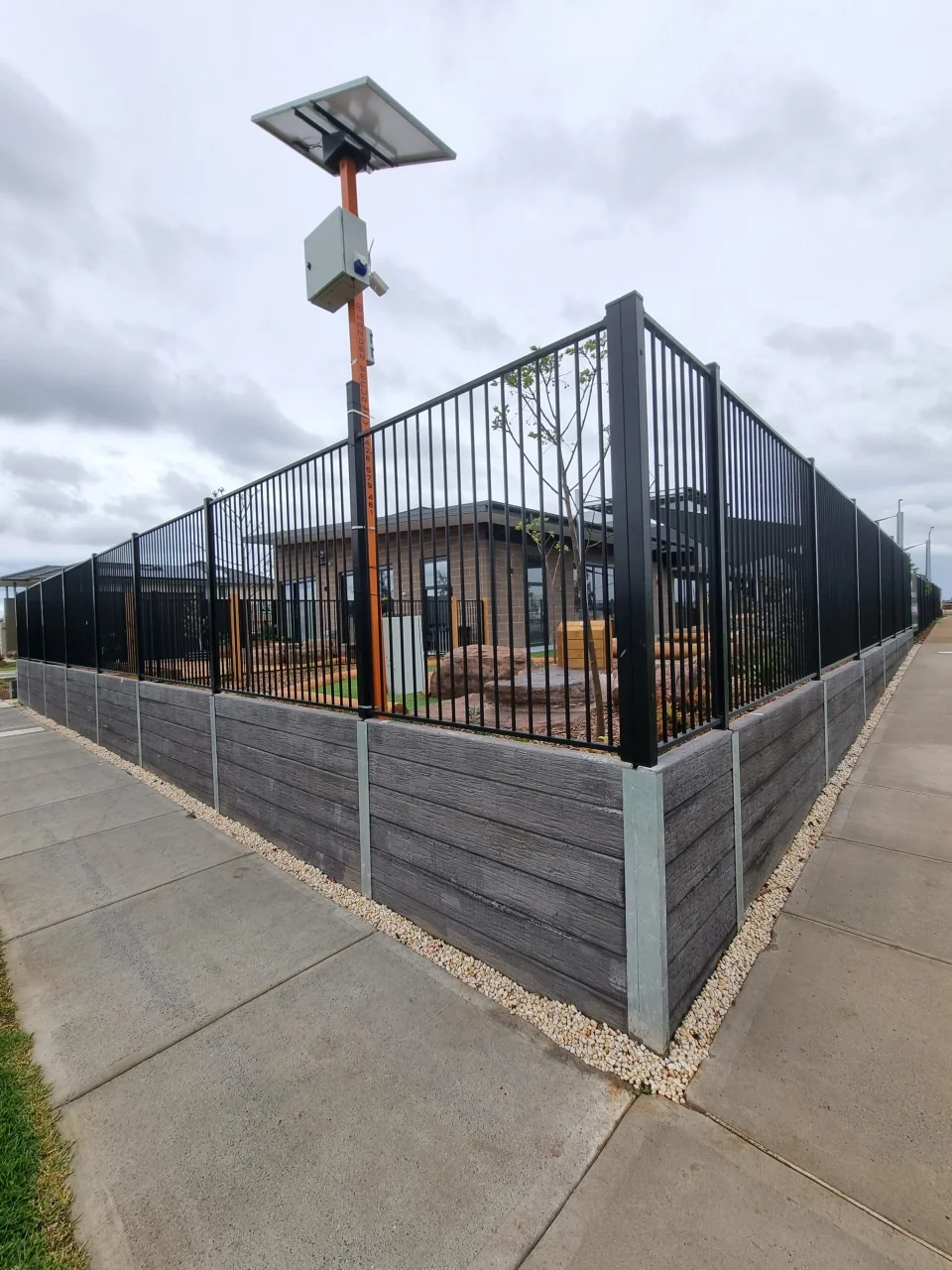 Corner view of Ashwood timber-look concrete sleeper walls with tubular fencing above in Derrimut