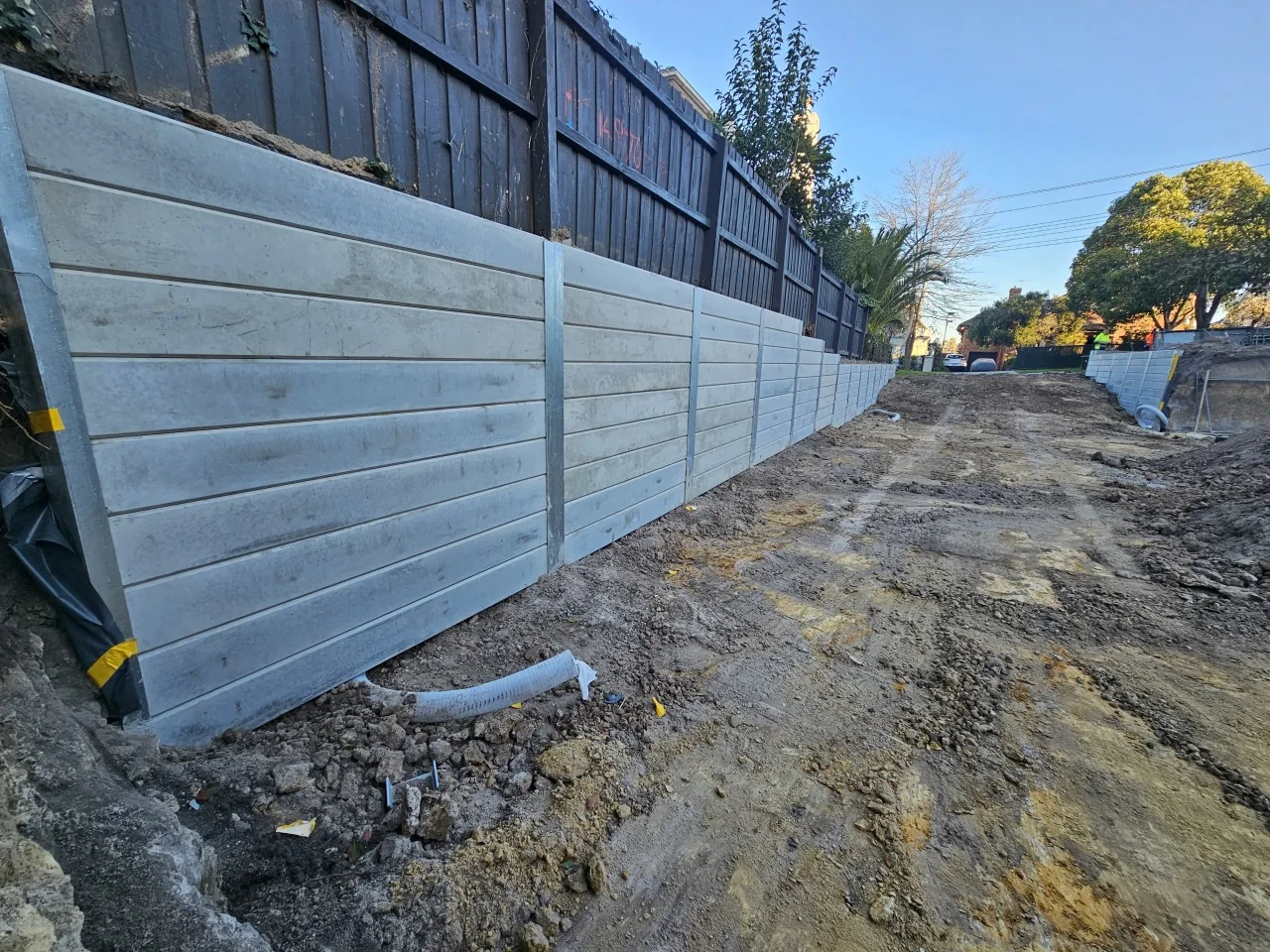 Concrete sleeper boundary retaining wall beneath an existing timber fence in Hawthorn