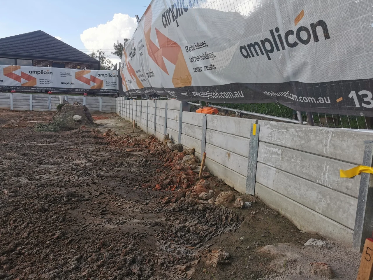 Concrete sleeper retaining wall beneath Amplicon site signage in Huntingdale
