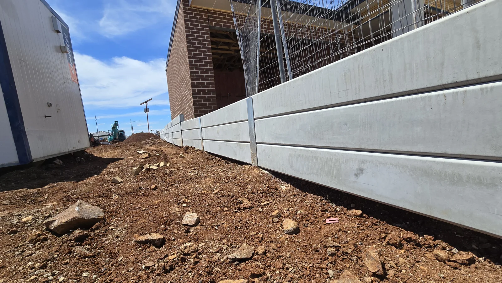 Long concrete sleeper retaining wall beside the brick building at Rockbank Childcare Centre