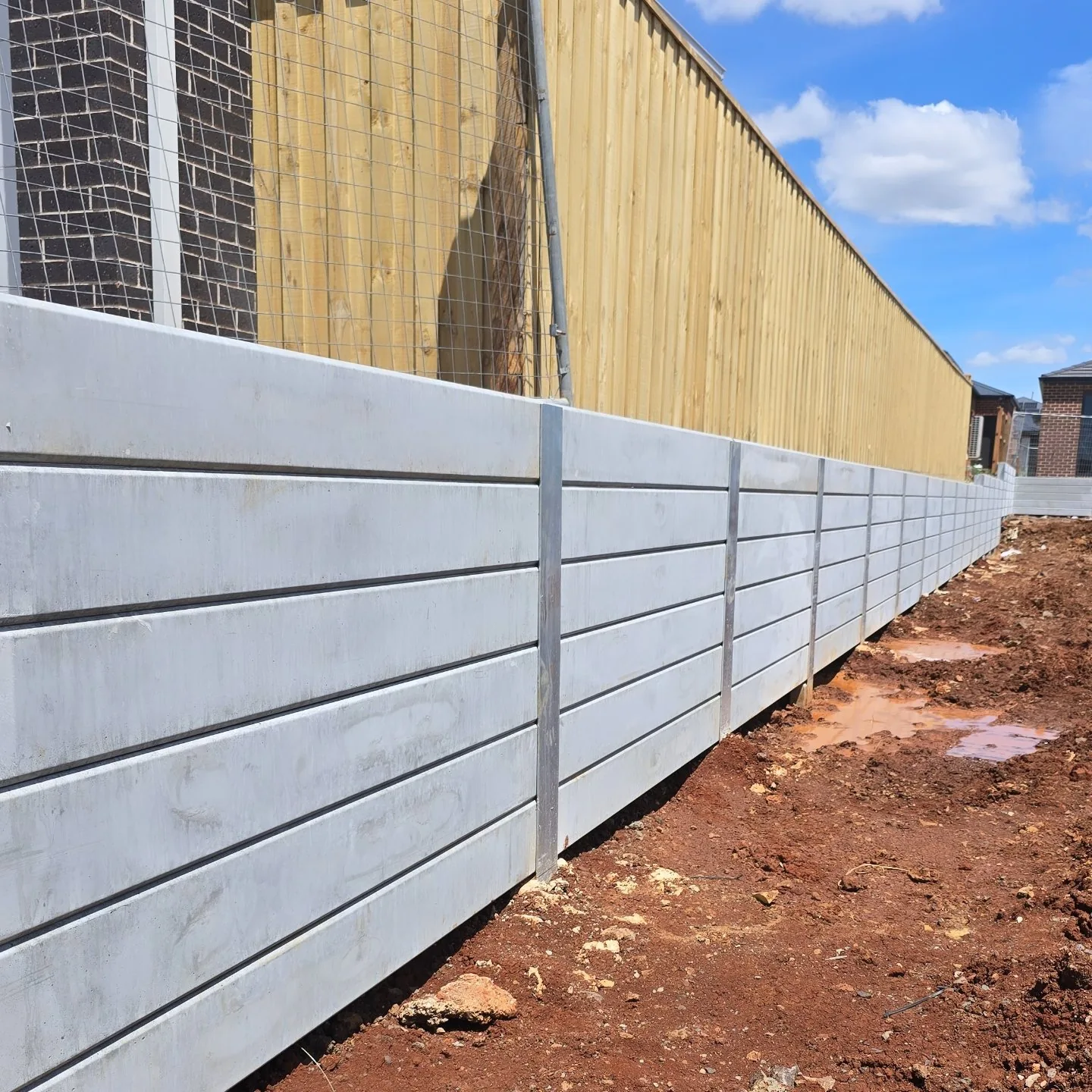 Concrete sleeper retaining wall along the timber boundary fence at Rockbank Childcare Centre