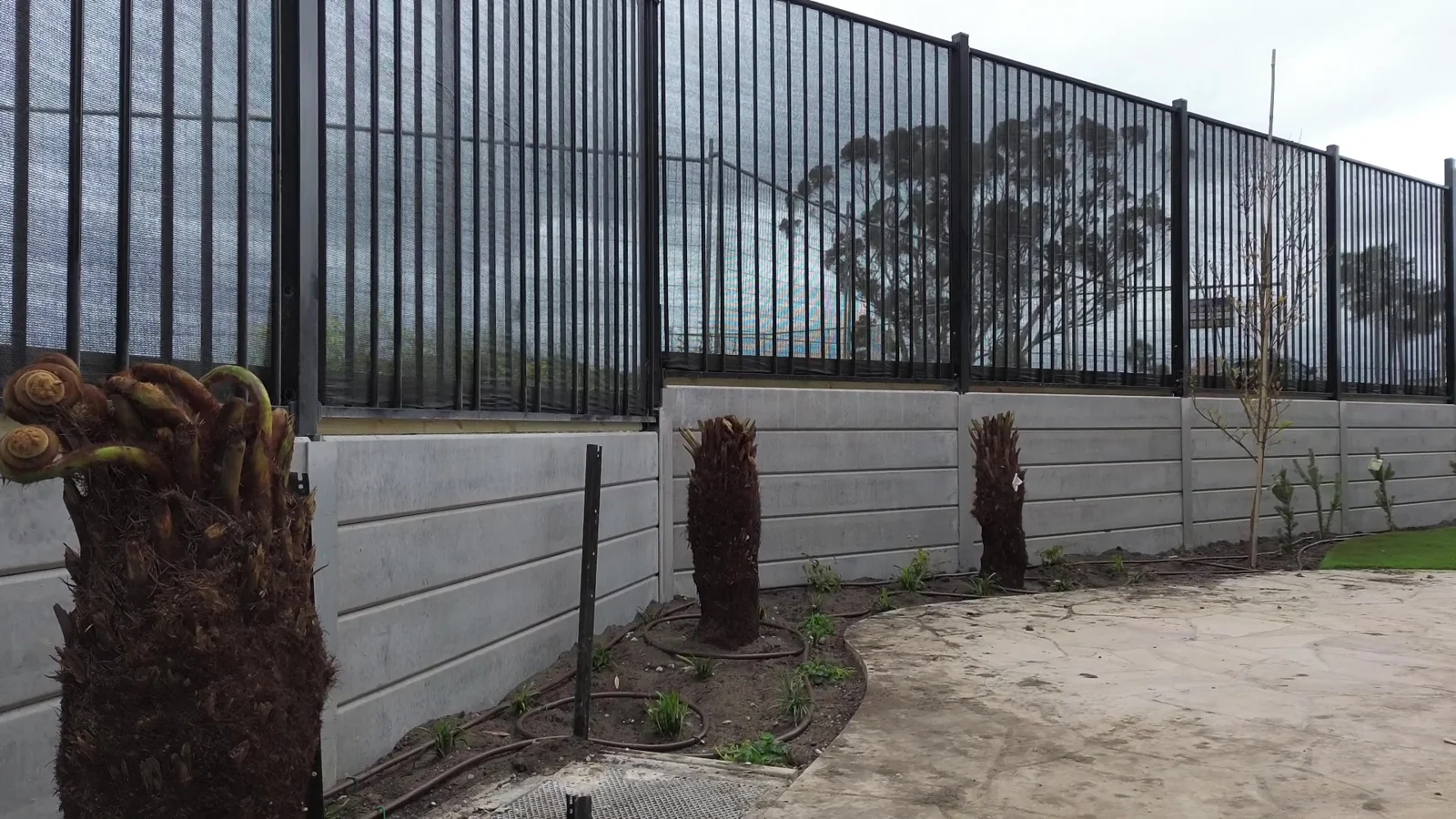 Concrete sleeper retaining wall with black tubular steel fencing above at the Sunbury childcare centre